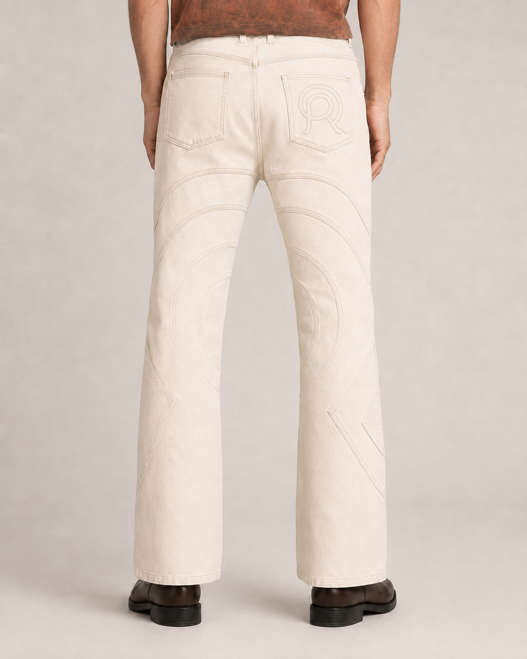 Model wearing the Limestone Voyager Denim Pant, back view, showing its slim fit and controlled flared silhouette.