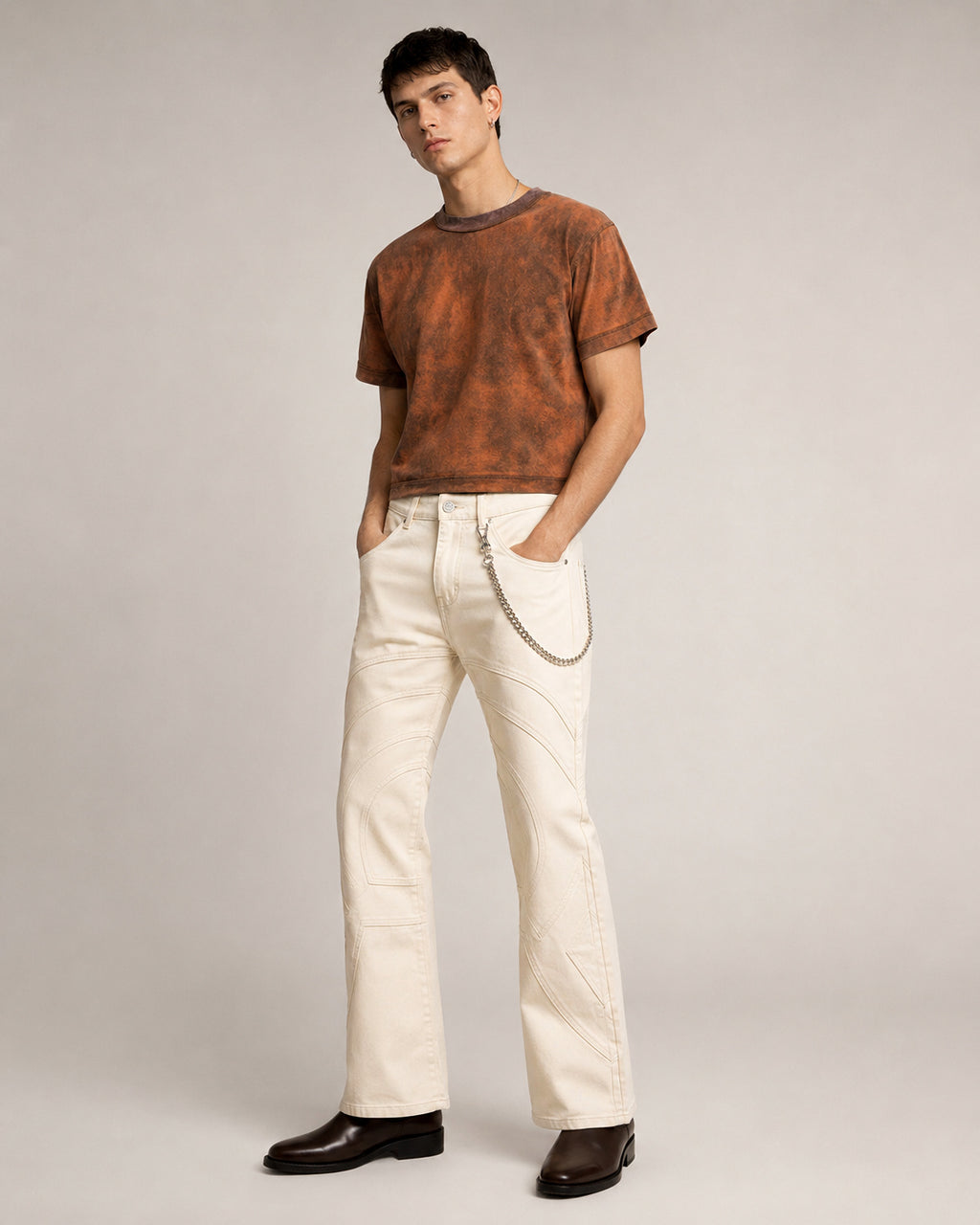 Model fully styled wearing the Sunfaded Reversible T-Shirt showing the dropped shoulder and waist-length crop and voyager denim pant in limestone from the side , showing the waist fit and flared-leg shape.